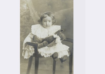 Lot 70 - A very large studio photograph of a young child holding a teddy bear, circa 1910