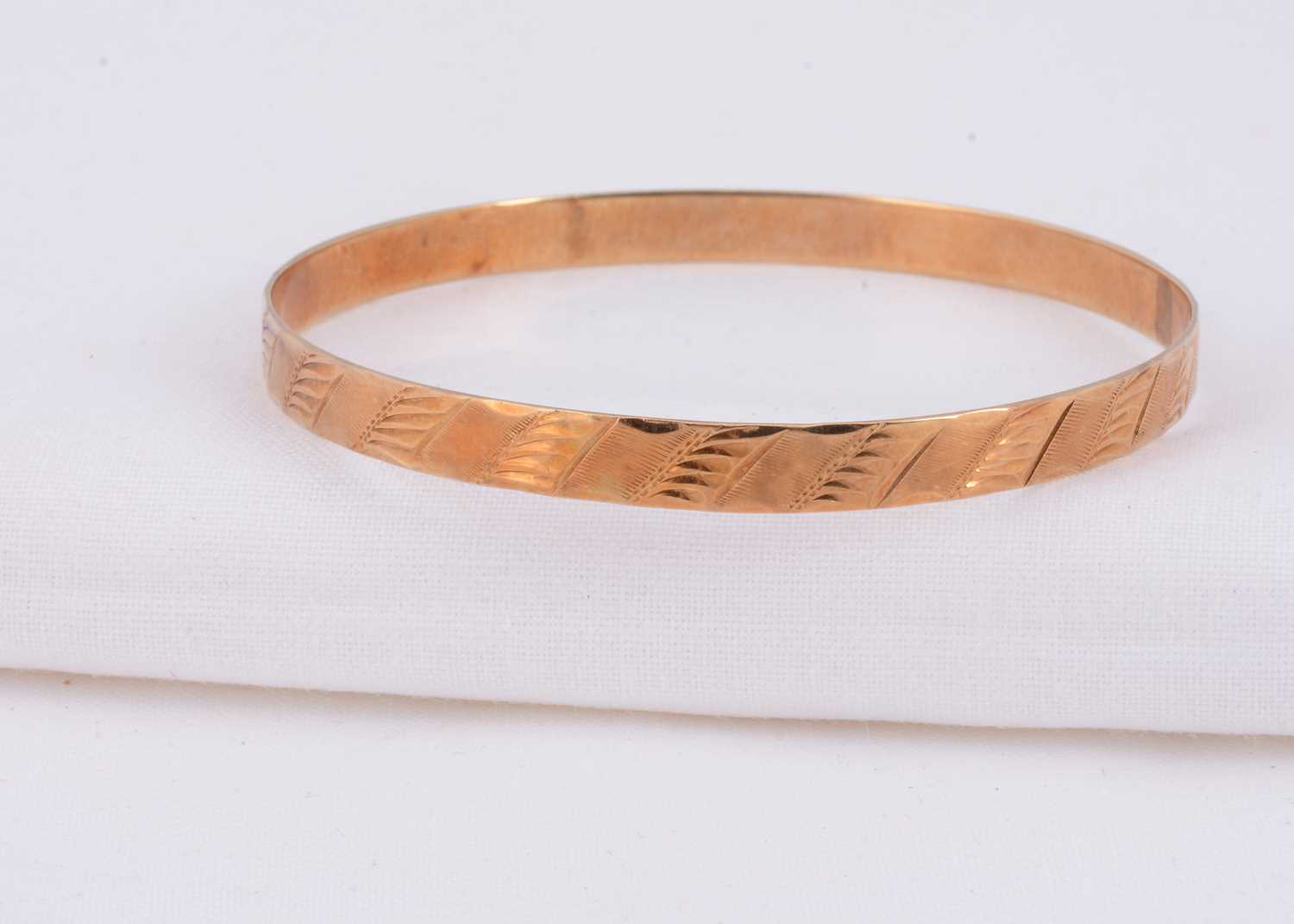Lot 63 - A 14k gold bangle with engraved design