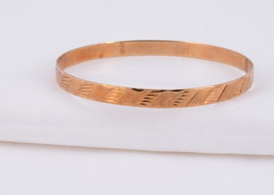Lot 63 - A 14k gold Russian bangle with engraved design