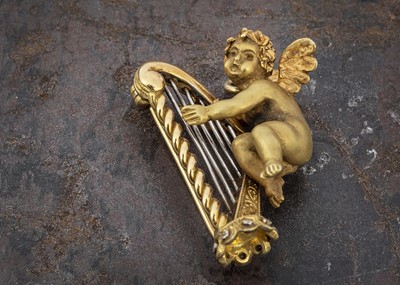Lot 36 - A Continental 18ct gold brooch or pendant depicting Cupid playing harp