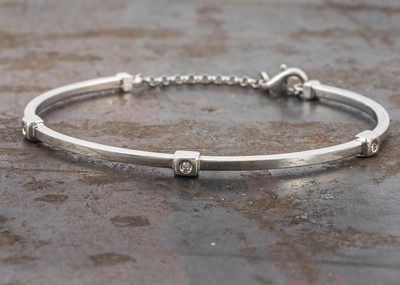 Lot 43 - An 18ct white gold diamond set torque and chain bangle