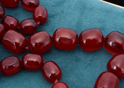 Lot 51 - A string of oval 'cherry amber' knotted strung beads