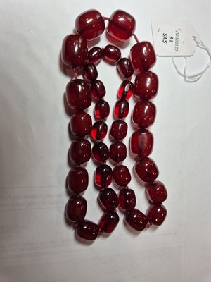 Lot 51 - A string of oval 'cherry amber' knotted strung beads