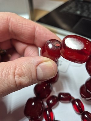 Lot 51 - A string of oval 'cherry amber' knotted strung beads
