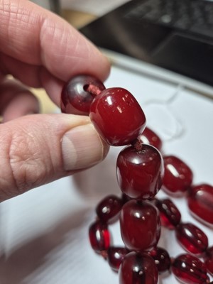 Lot 51 - A string of oval 'cherry amber' knotted strung beads