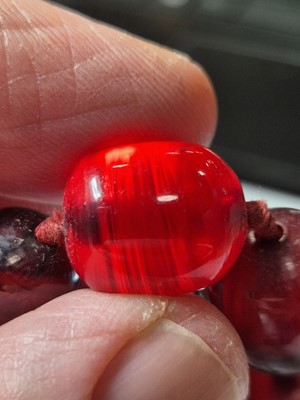 Lot 51 - A string of oval 'cherry amber' knotted strung beads