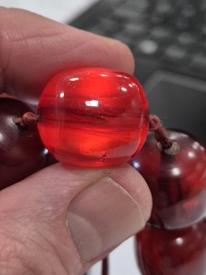 Lot 51 - A string of oval 'cherry amber' knotted strung beads