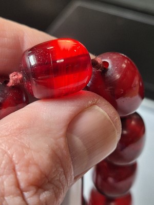 Lot 51 - A string of oval 'cherry amber' knotted strung beads