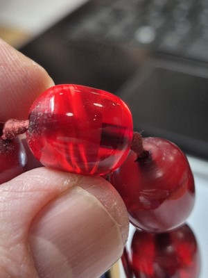 Lot 51 - A string of oval 'cherry amber' knotted strung beads