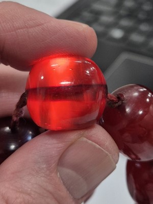Lot 51 - A string of oval 'cherry amber' knotted strung beads