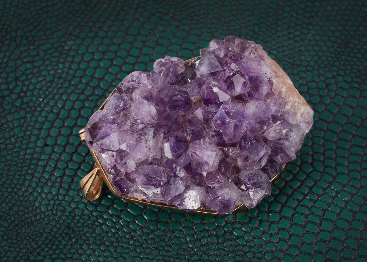 Lot 3 - A natural amethyst crystal framed in yellow metal