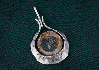 Lot 33 - A continental silver rock crystal and rutile abstract pendant