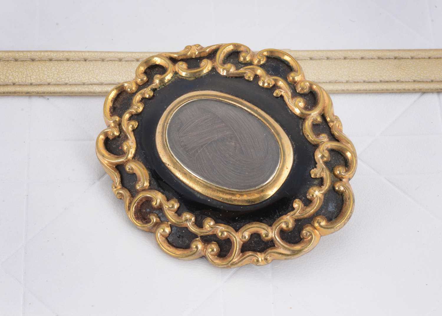 Lot 38 - A 19th Century oval gilt metal black enamel and plaited hair mourning brooch