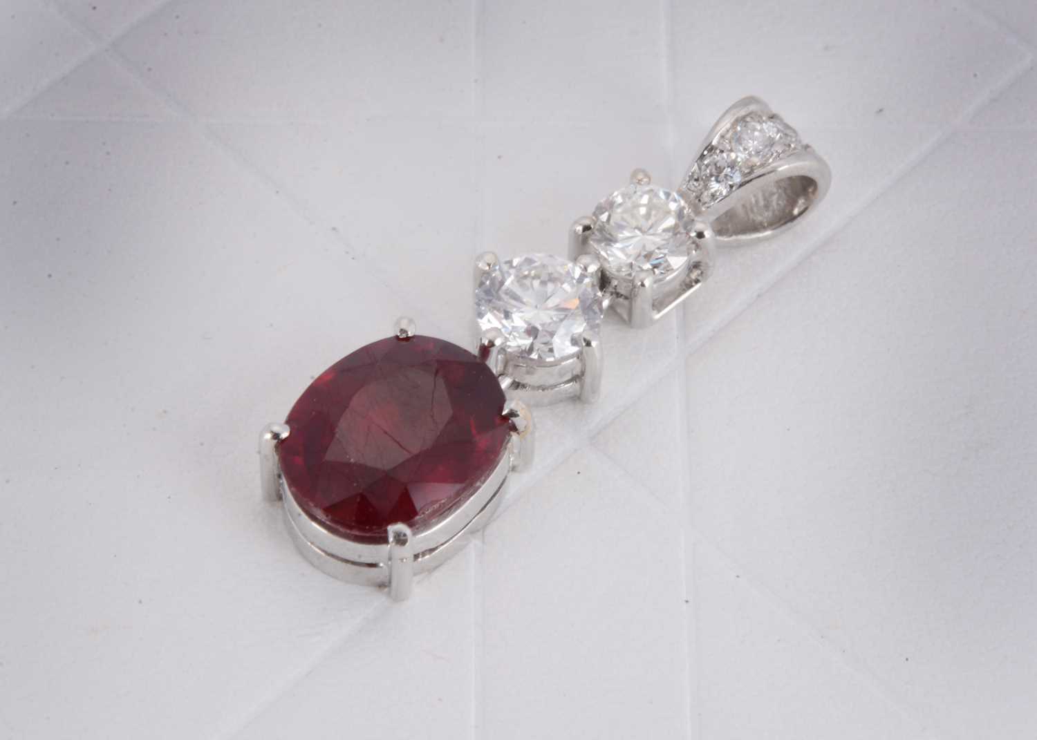 Lot 153 - A 750 marked white metal ruby and diamond drop pendant