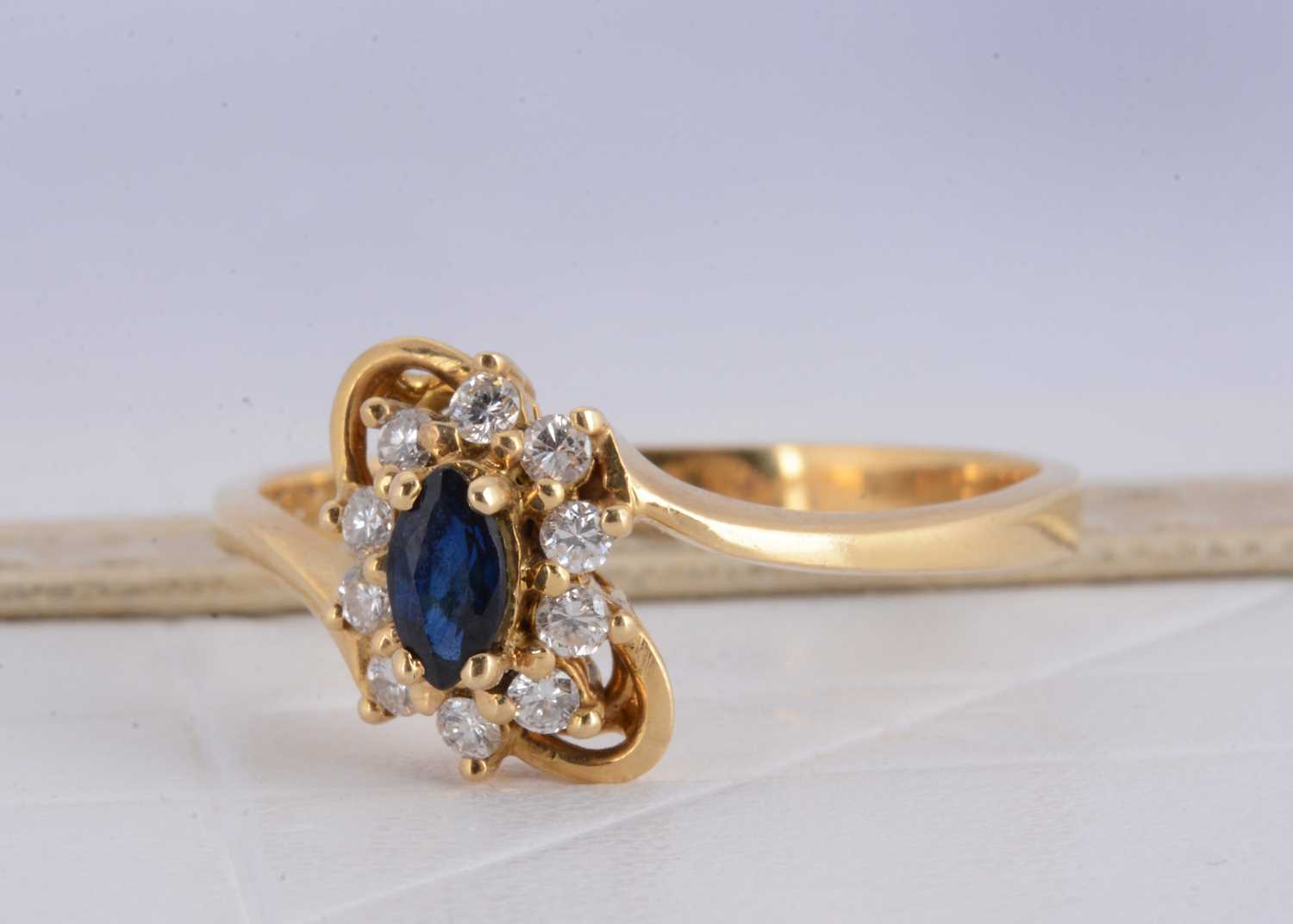 Lot 155 - A 750 marked yellow metal sapphire and diamond cluster crossover ring