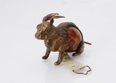 Lot 1254 - An early 20th century brass and faux tortoiseshell rabbit tape measure