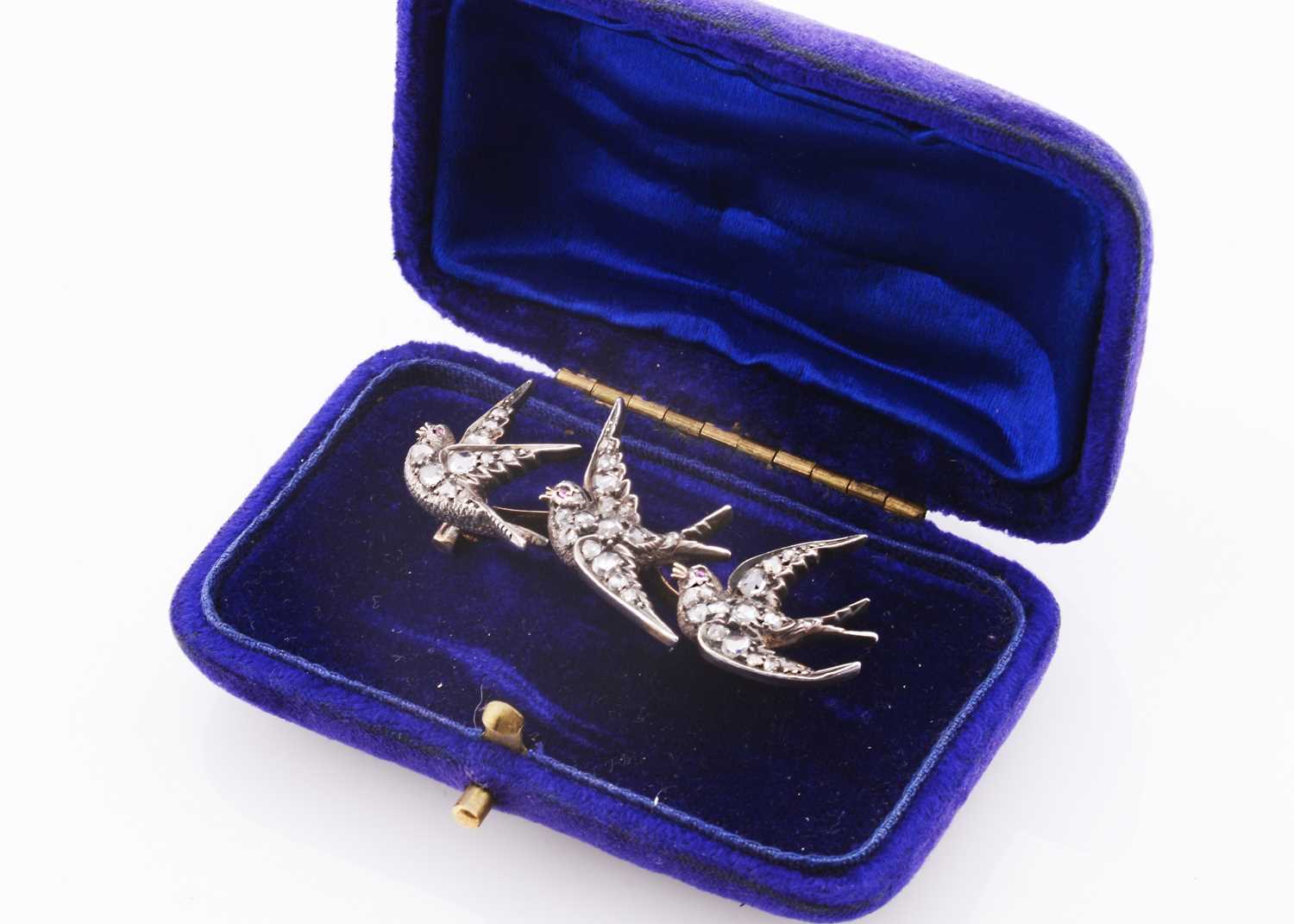 Lot 221 - A white metal three swallows in flight, diamond set brooch