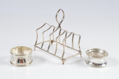 Lot 415 - A George VI toast rack by Thomas Bradbury and two napkin rings